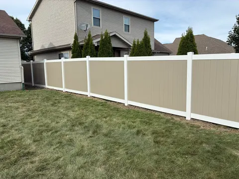 Tan privacy infill contrasts with white posts and rails.