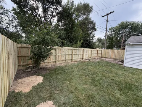 The rail side of a wood privacy fence, with horizontal rails and upright posts visible.