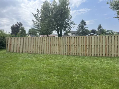 Long wood shadowbox fence with alternating boards.