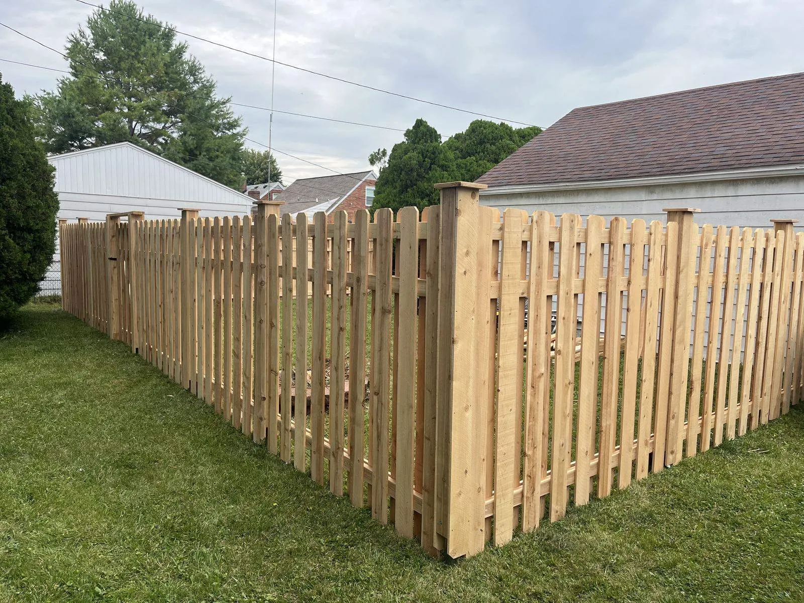 Cedar spaced picket fence with post caps at a corner
