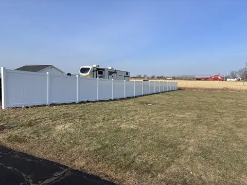 Long white privacy fence beside an open lawn.