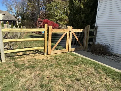 Wire mesh continues across the rail fence and both diagonally braced gate leaves.