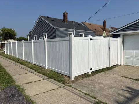 White privacy fence and gate beside a sidewalk.