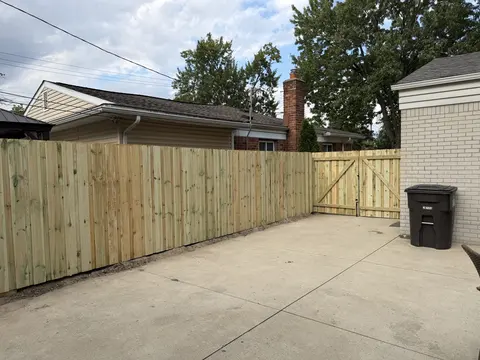 Privacy fence along a driveway ending at a double gate